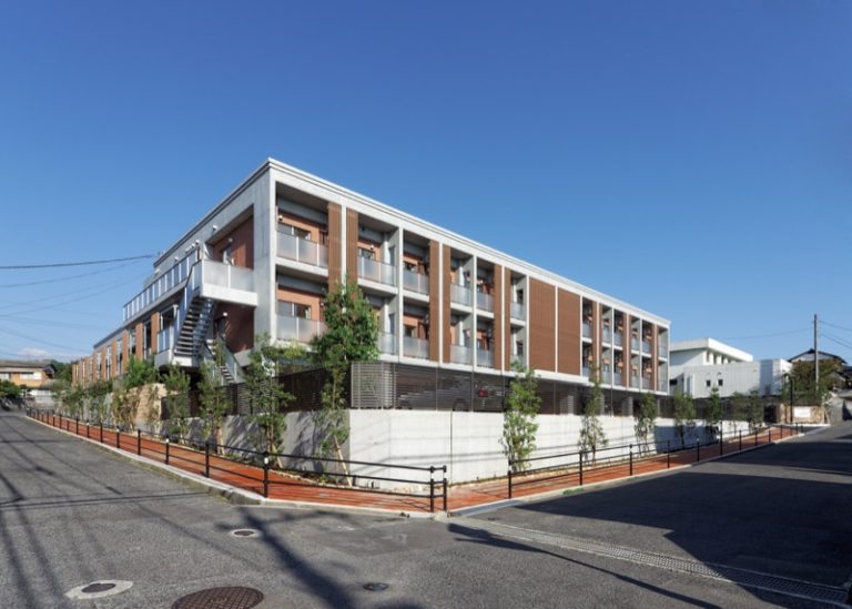 現代的な介護施設の建物外観。3階建ての白とブラウン基調の新築施設。